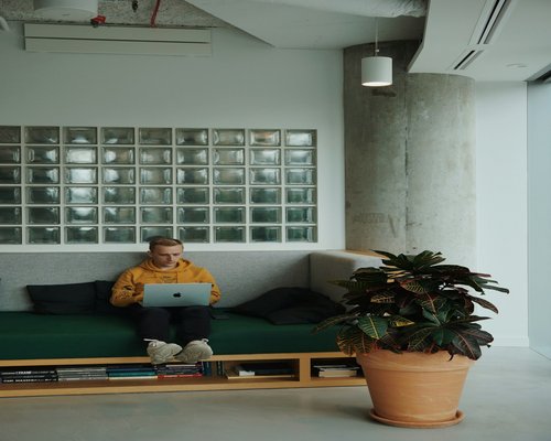 A modern cozy editorial table with notebooks, plants, and sunlight flowing through windows in Warsaw office