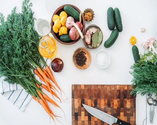A bright kitchen counter with fresh organic vegetables, wooden cutting board, and olive oil ready for home cooking